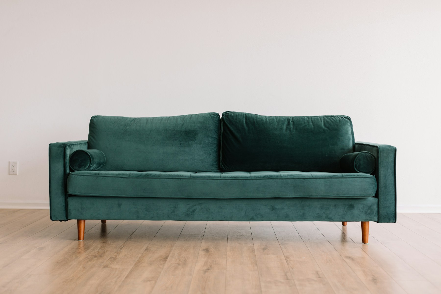 Green upholstered sofa with tapered timber legs and a clean mid-century silhouette